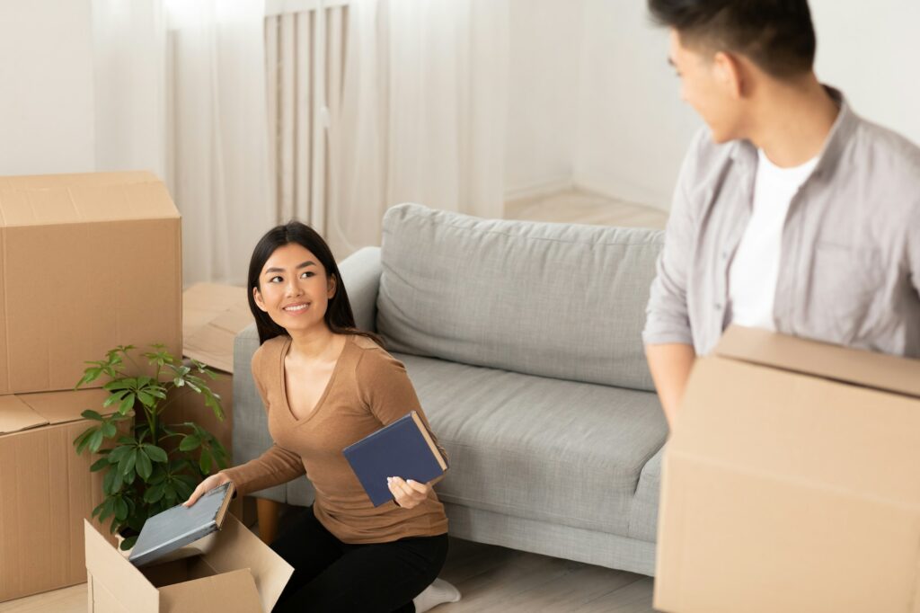 Happy asian man and woman unpacking in dorm